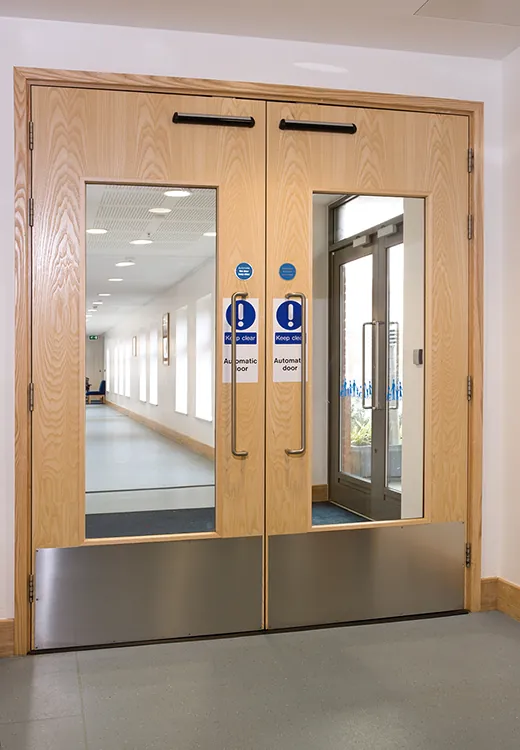 Double timber fire doors with vision panels and safety signage
